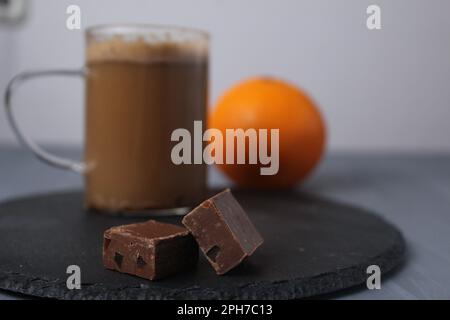 chocolate candy with coffee and orange slices on a grey tray with coffee and orange in the background. Handmade candies. Dessert and coffee. Stock Photo