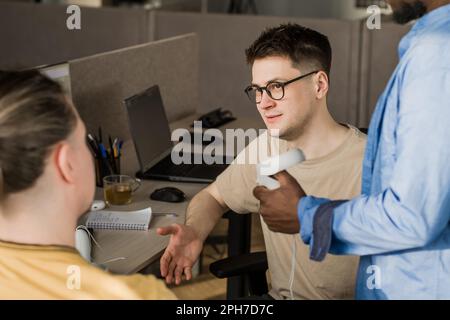IT Development Team Working on VR Project. Man wearing VR headset, playing and touching something in the virtual world. Diverse men programmers using Stock Photo