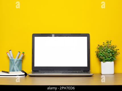 Blank white screen laptop computer on desktop yellow background. Stock Photo
