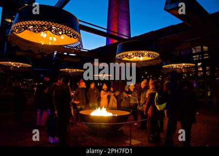 Toronto, Ontario / Canada - March 04, 2018: Bonfire around people. Basking by the fire at night.  Outdoor activities in the Toronto Light Festival. Stock Photo