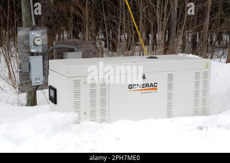 A Generac Protector QS, a backup electric generator that runs on propane or natural gas sitting in the snow in the Adirondack Mountains, NY US Stock Photo