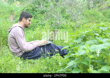 A man working with laptop in nature. Work outdoor concept idea. Stock Photo
