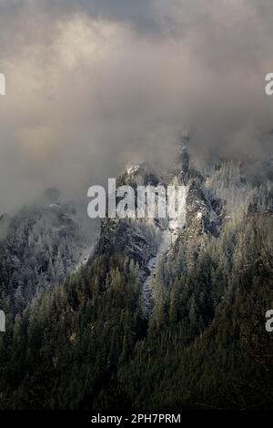 Snow covered mountains rising into winter clouds in the Washington Cascades Stock Photo