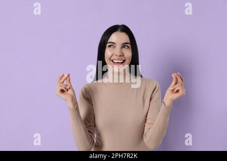 Young woman snapping fingers on violet background Stock Photo