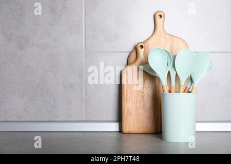 Holder with kitchen utensils and cutting boards on grey table. Space for text Stock Photo