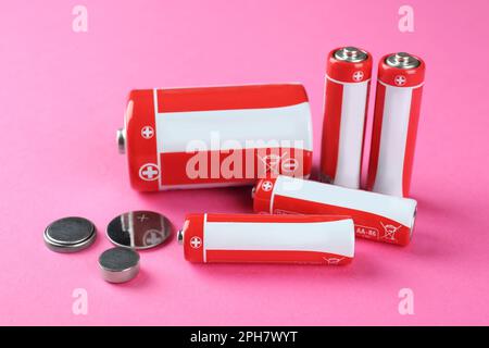 Different types of batteries on pink background Stock Photo
