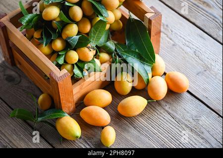 Marian plum fruit and leaves in b wooden box, tropical fruit Name in Thailand Sweet Yellow Marian Plum Maprang Plango or Mayong chid Stock Photo