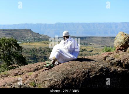 An Ethiopian Orthodox priest sitting above a Rock-hewn church in Lalibela, Ethiopia. Stock Photo