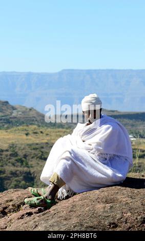 An Ethiopian Orthodox priest sitting above a Rock-hewn church in Lalibela, Ethiopia. Stock Photo