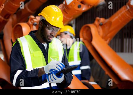 Two young engineer man checking and maintenance machine robot arms technology intelligence and innovation at factory industrial, people or technician Stock Photo