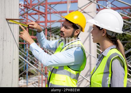 Engineer young man and woman using tape measure for check and examining length of structure at construction site, architect or contractor inspection a Stock Photo