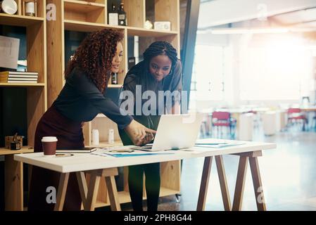 Success requires proper planning. two businesswomen discussing something on a laptop at the office. Stock Photo