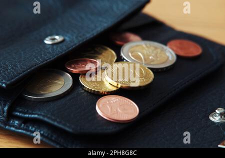 Euro coins in black wallet on wooden table Stock Photo