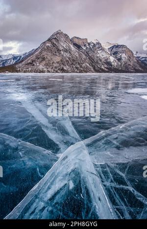 Cracks in the ice of Lake Minnewanka with Mount Inglismaldie in Banff National Park in the background Stock Photo