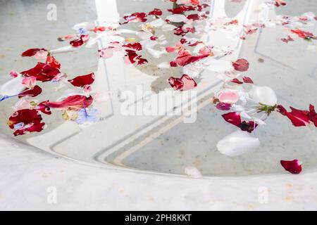 Reflection of an old and historic Marrakech palace in a fountain with white and red rose petals floating Stock Photo