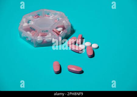 Organizer weekly shots on blue background with Copy space for your text. Closeup of medical pill box with doses of tablets for daily take medicine with white pink drugs and capsules. Daily vitamins at home. Medication dietary supplements, immunity and disease prevention Fish oil softgel, vitamin D and C omega minerals, fiber, fatty amino acids, probiotics sedatives. Health care and diseases cure Stock Photo