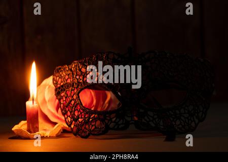 a candle flame and next to one rose in the dark close-up Stock Photo