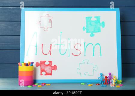 MYKOLAIV, UKRAINE - DECEMBER 30, 2021: White board with word Autism, stationery and toys on light blue wooden table Stock Photo