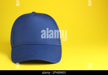 Stylish blue baseball cap on yellow background. Space for text Stock Photo