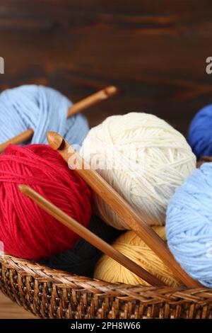 Clews of colorful knitting threads and crochet hooks in wicker basket, closeup Stock Photo