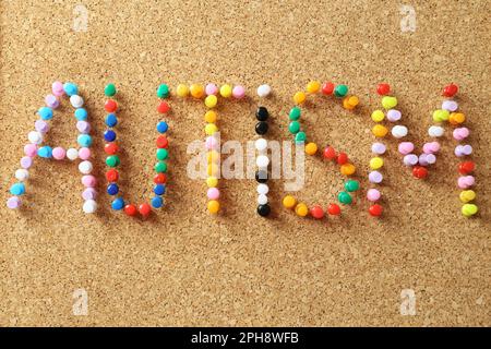 Word Autism made of colorful pins on cork board, closeup Stock Photo