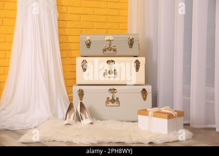 Storage trunks, shoes and gift box near yellow brick wall indoors. Interior design Stock Photo