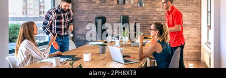 Colleagues talking in office while two of them having fun playing ping pong over coworking table Stock Photo
