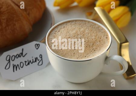 Cup of coffee, croissant and card with phrase GOOD MORNING on white tray, closeup Stock Photo