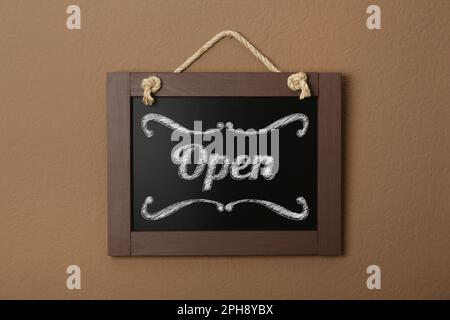 Small chalk board with word Open on brown wall Stock Photo
