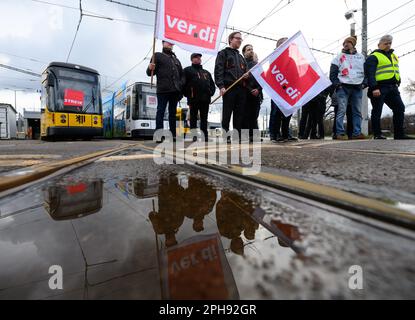 Dresden, Germany. 27th Mar, 2023. Employees of the Dresdner Verkehrsbetriebe (DVB) stand with Verdi flags in front of streetcars during the warning strike at the Trachenberge depot. With a large-scale nationwide warning strike, the unions EVG and Verdi have paralyzed large parts of public transport on Monday. Credit: Robert Michael/dpa/Alamy Live News Stock Photo