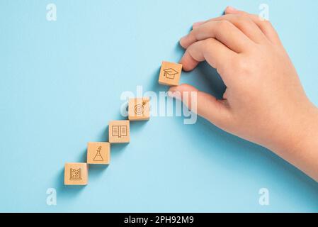 Student organizing wooden cubes with education icons. Education concept Stock Photo