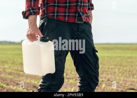 Corn crop protection concept, male farmer agronomist holding jerry can container canister with pesticide, selective focus Stock Photo