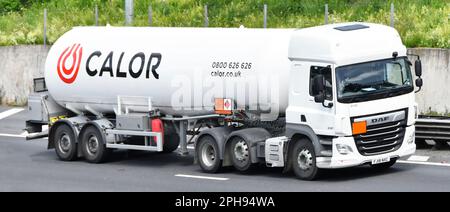 Side & front view white DAF CF prime mover hgv lorry truck driver & Calor Gas articulated trailer with Hazchem plates driving on M25 motorway road UK Stock Photo