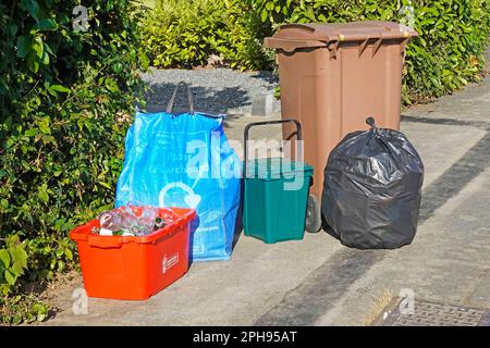 Segregated rubbish pavement weekly collection by council red glass bin blue paper card sack green food bin brown wheelie garden black non recyclable Stock Photo