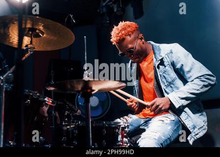 Plays drums. Young african american performer rehearsing in a recording studio Stock Photo