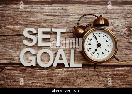 Set Goal alphabet letter and alarm clock on wooden background Stock Photo