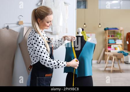 Dressmaker with measuring tape working in atelier Stock Photo