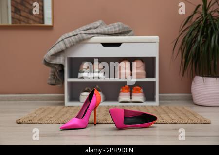Shelving unit and stylish shoes on floor in hall Stock Photo