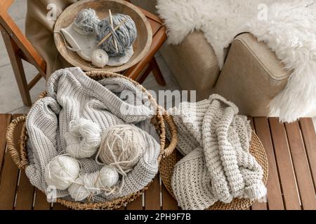 Basket with threads for knitting on a wooden bench in the interior of the room. Stock Photo