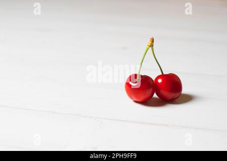 Two cherries on a white table Stock Photo
