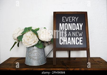 Every Monday It's a new Chance text message on easel blackboard standing on wooden shelves Stock Photo