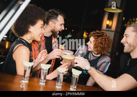 https://l450v.alamy.com/450v/2ph9mmm/side-view-of-multiethnic-friends-with-different-cocktails-talking-near-blurred-tequila-glasses-in-barstock-image-2ph9mmm.jpg