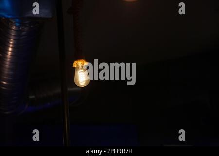 Picture of lightbulbs hnging from the roof, lighting and shining with a typical incandescent yellow light, in an industrial themed room. Stock Photo