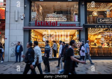 Picture of a crowd of blurred people passing on istiklal street of istanbul, in front of a shop selling dried fruits and nuts and pastries. Stock Photo