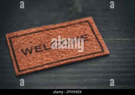 Old Welcome door mat on black wooden background, welcome concept, home concept Stock Photo