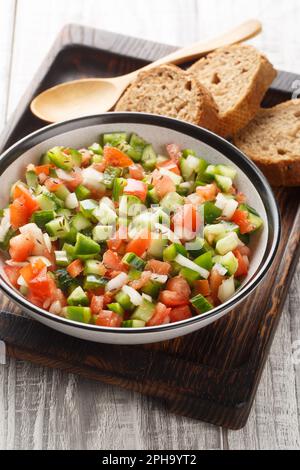 Summer Spanish Salad Pipirrana with green pepper, tomatoes, cucumber, onion and caraway closeup on the plate on the table. Vertical Stock Photo