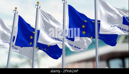 Frankfurt, DE, March 2023: Five Flags of the European Central Bank and European Union waving in the wind with the ECB seat blurred on background. Illu Stock Photo