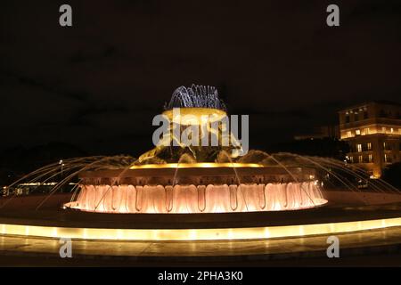 The Tritons’ Fountain (at night) is a fountain located just outside the City Gate of Valletta, Malta. It consists of three bronze Tritons holding up a large basin, balanced on a concentric base built out of concrete and clad in travertine slabs. The fountain is one of Malta's most important Modernist landmarks. Designed and constructed between 1952 and 1959. The bus terminal and station is located nearby. Stock Photo