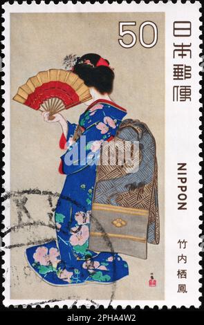 Geisha with fan on japanese postage stamp Stock Photo