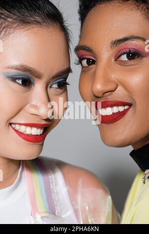 Close up view of smiling interracial models with red lips and visage on grey background,stock image Stock Photo